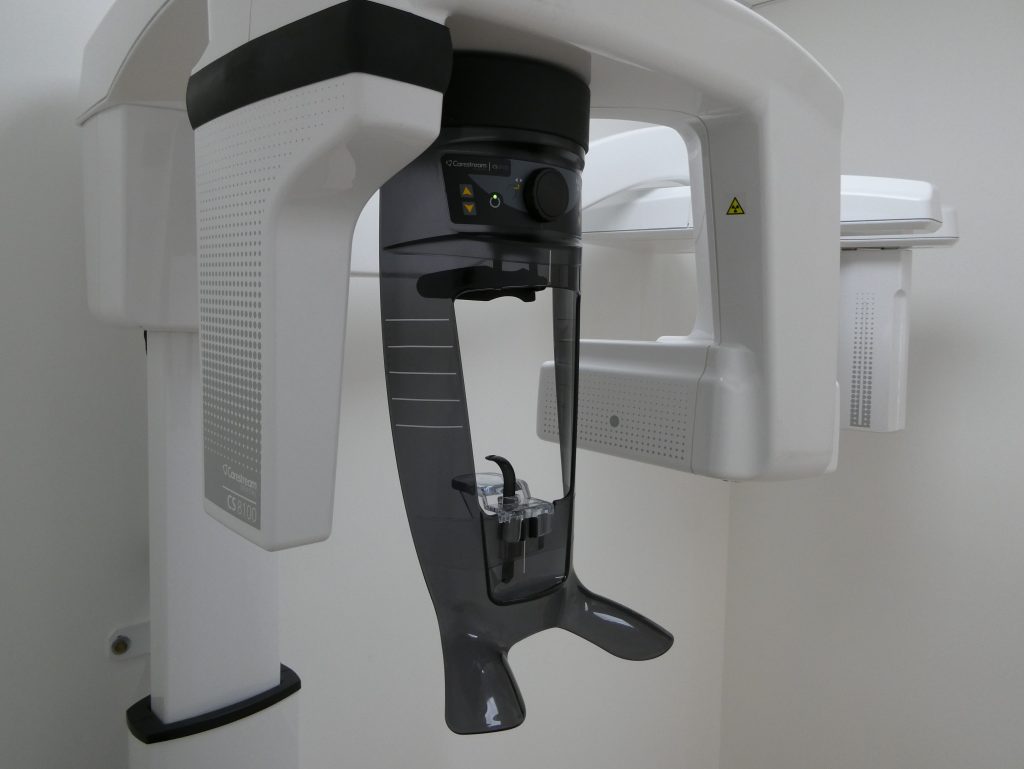 illustration arc blessant Gros plan dun appareil de radiographie panoramique dentaire dans un cabinet dentaire, montrant les composants du bras de positionnement du patient et de lappui-tête sur un fond uni.